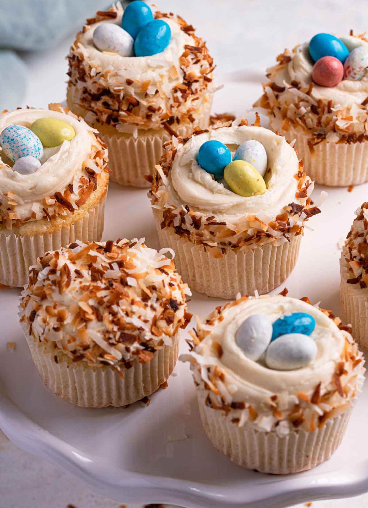 Multiple coconut cupcakes topped with toasted coconut and malted Whopper Robin Eggs.