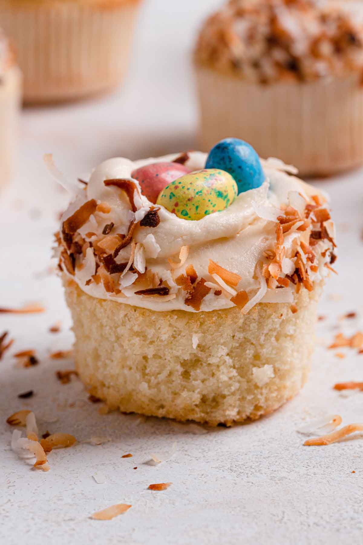 Single coconut cupcake with paper liner removed.