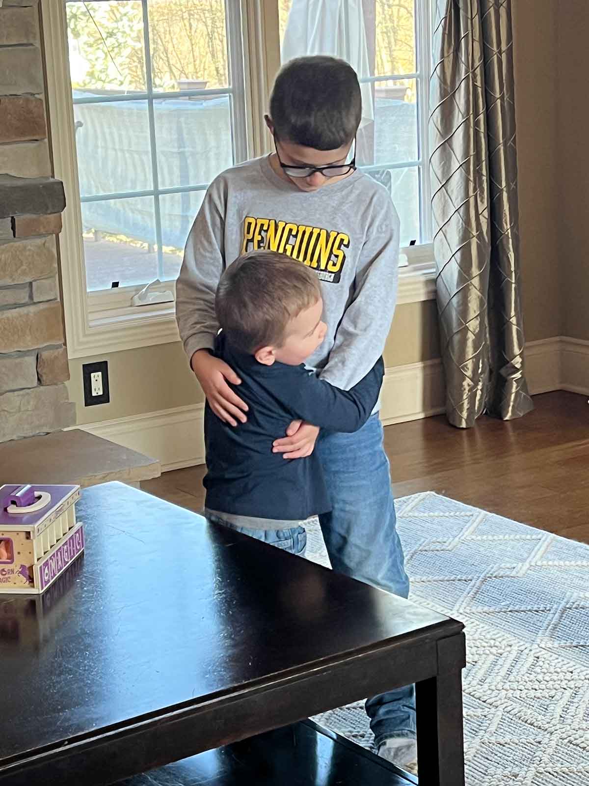 Bigger boy hugging a toddler.