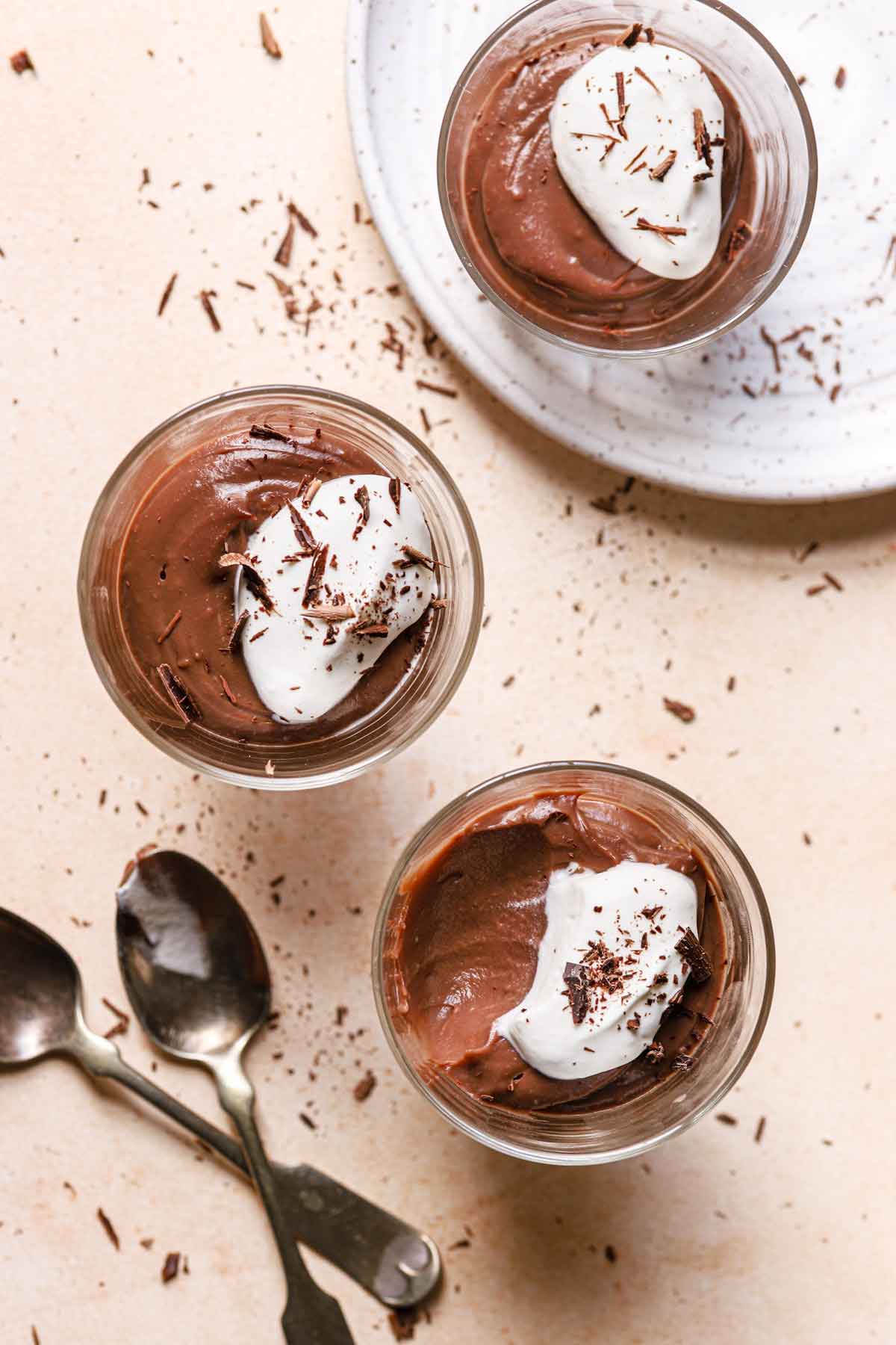 Overhead photo of three glass cups filled with chocolate pudding and a spoonful taken out of one.