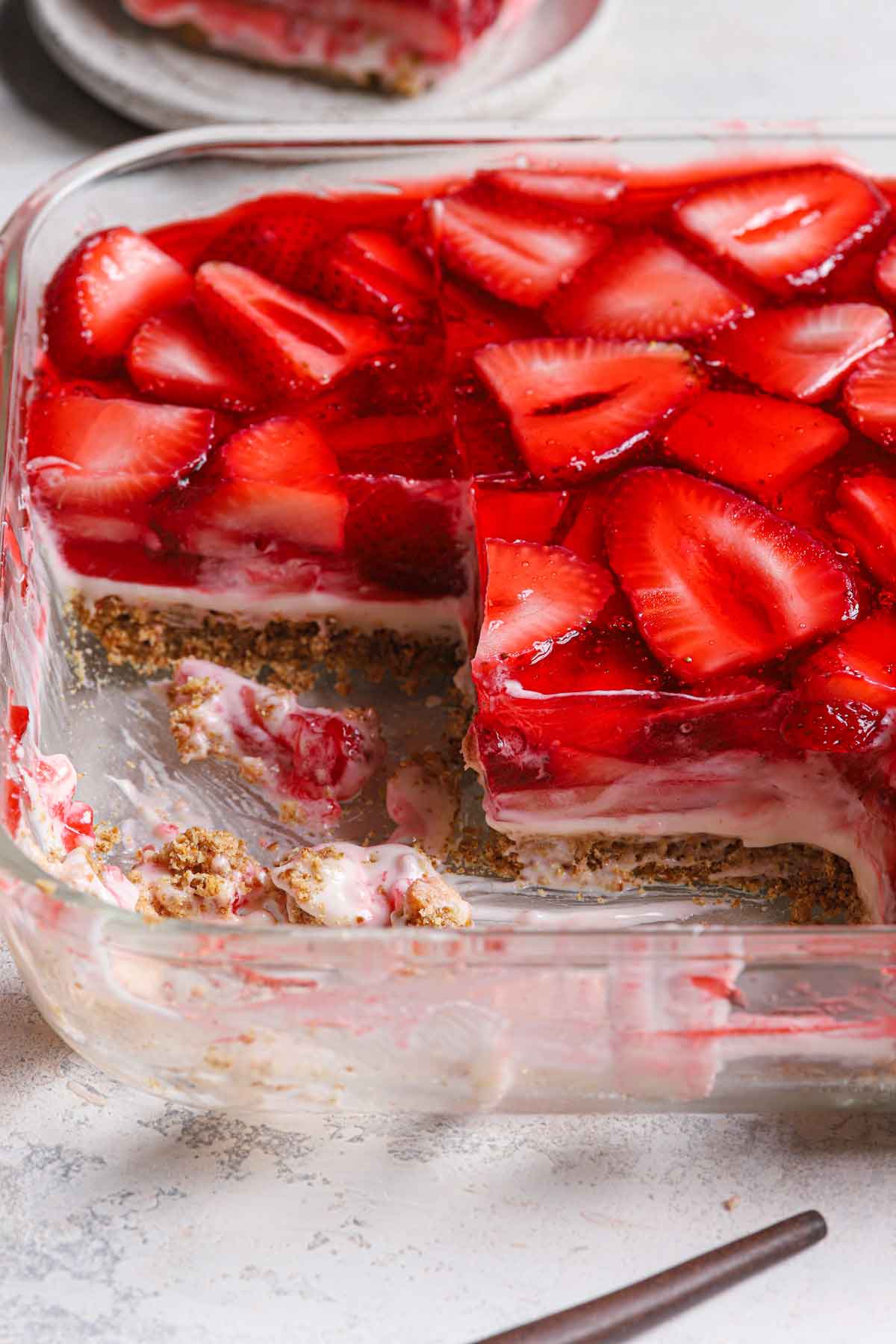 Photo of strawberry pretzel salad in a glass baking pan with a few slices removed.