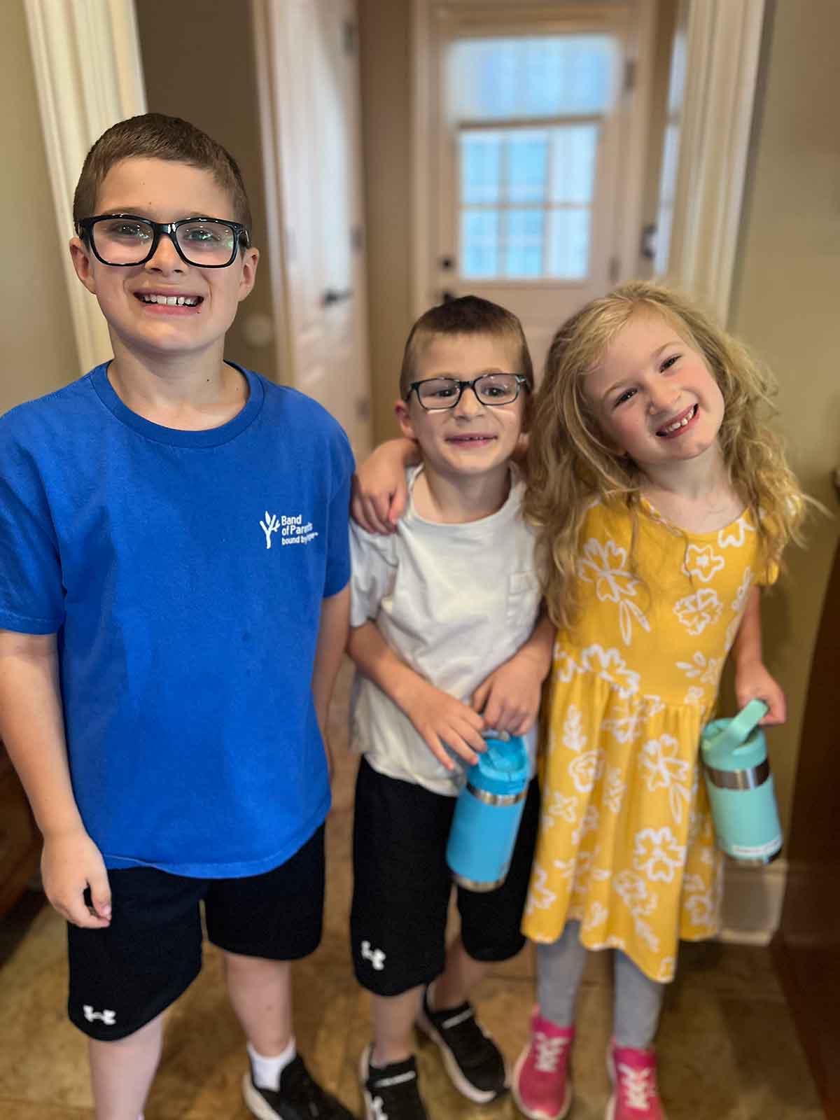 Two boys and a girl with their arms around each other.