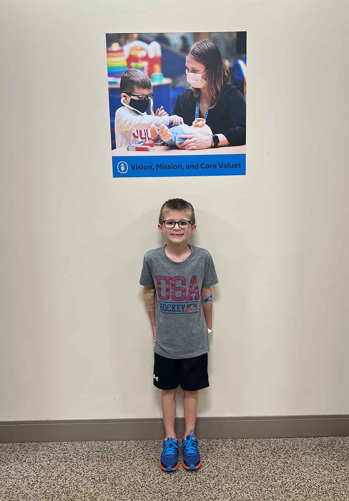 Little boy standing underneath a poster of himself.