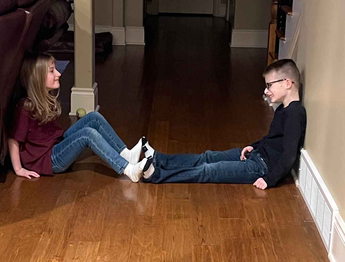 Boy and girl sitting facing each other with their feet touching.