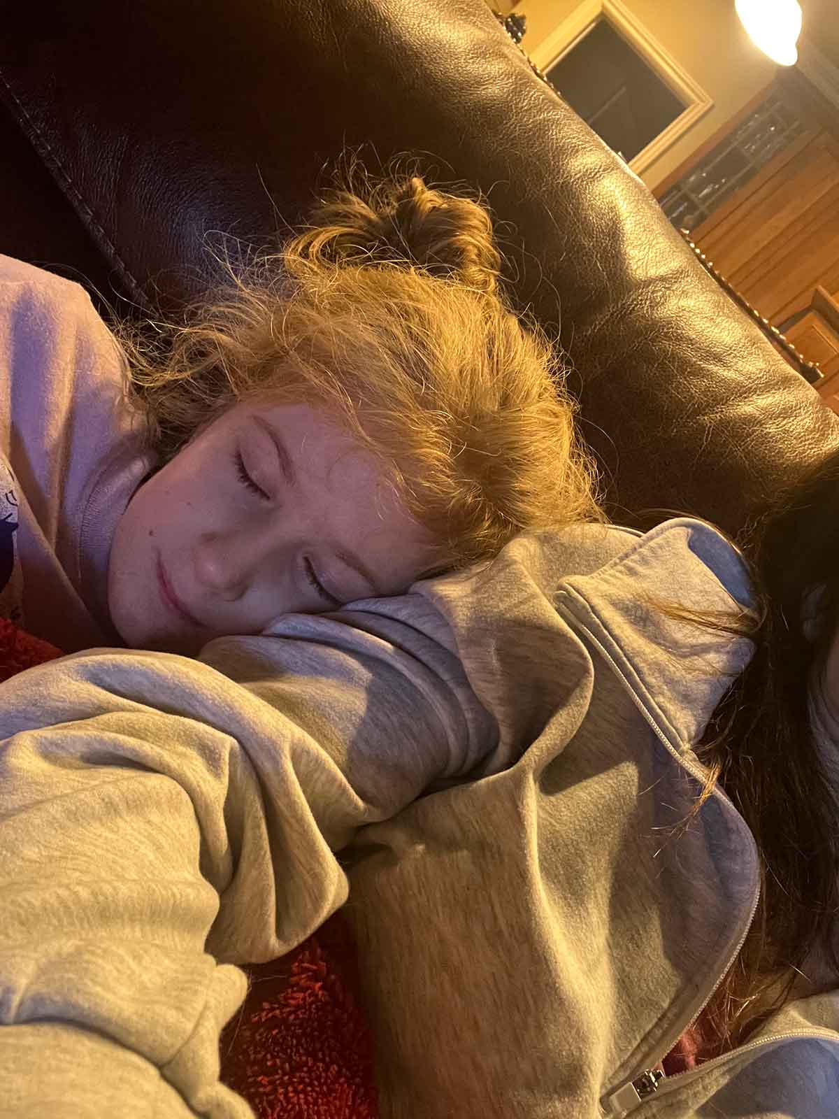 Little girl snuggled up on the couch against her mom's shoulder.