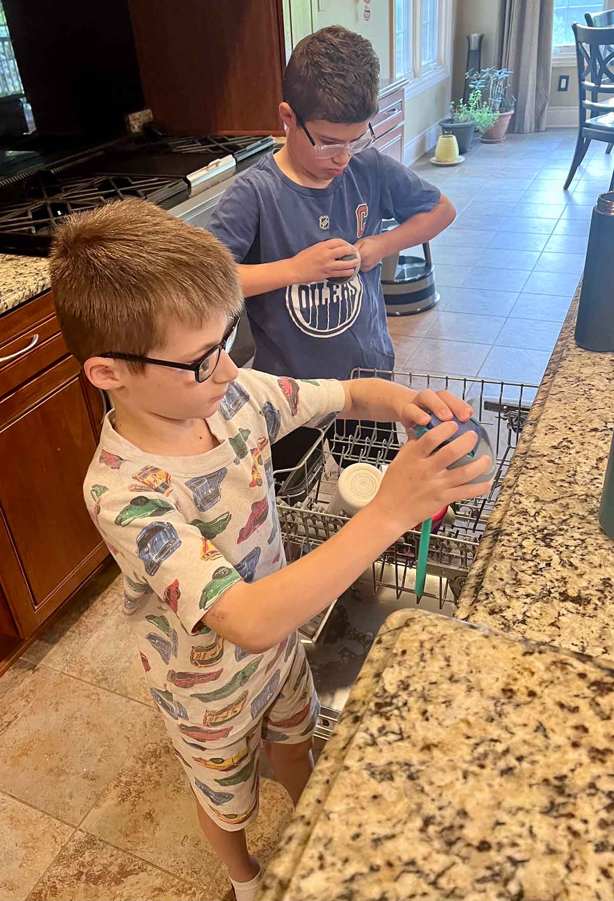 Two boys unloading a dishwasher.