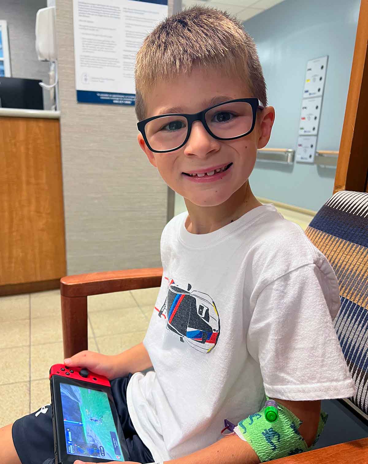 Little boy sitting in a hospital waiting room playing a Nintendo Switch.