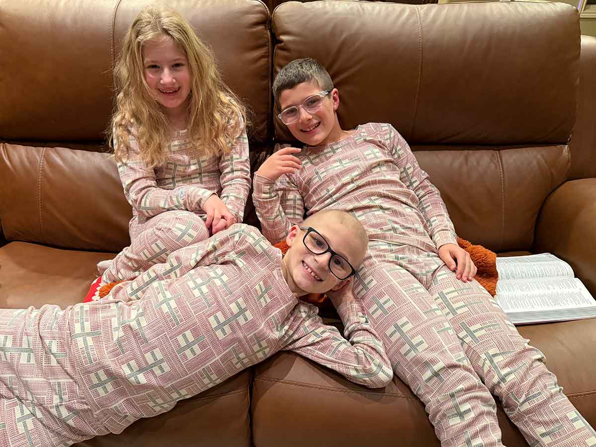 Three kids, two boys and a girl, in pajamas on Christmas Eve.