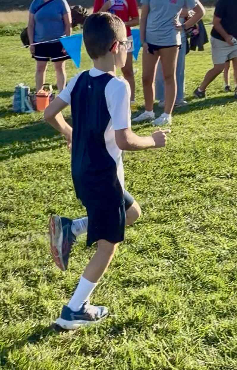 Young boy running a cross country race.